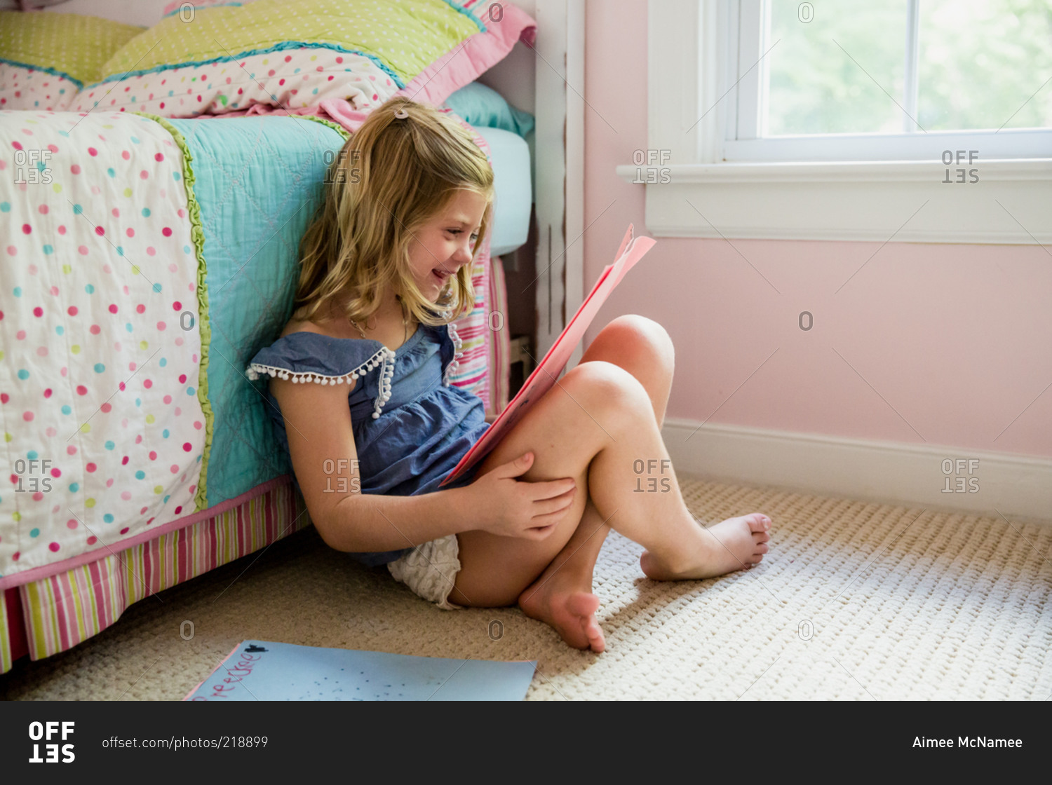 Young girl in pink bedroom looking at drawings