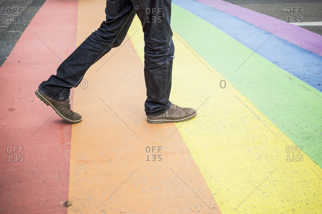 Man walking on rainbow flag painted on the street