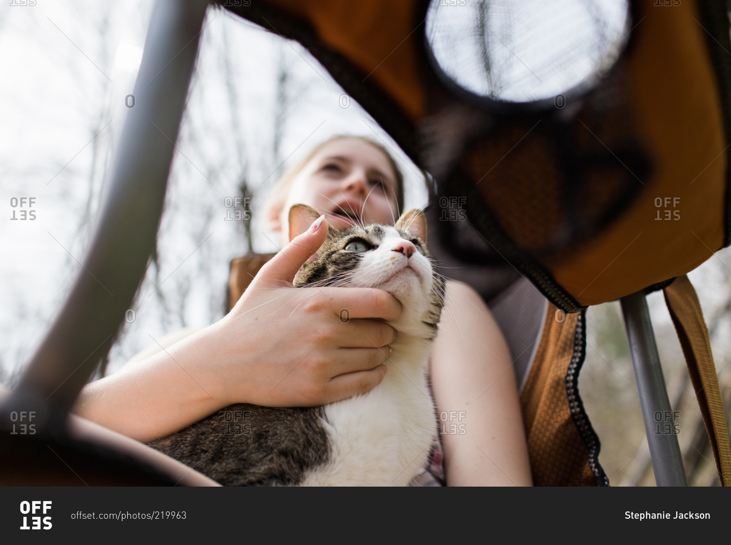 Teen girl in a camp chair scratches her cat's chin