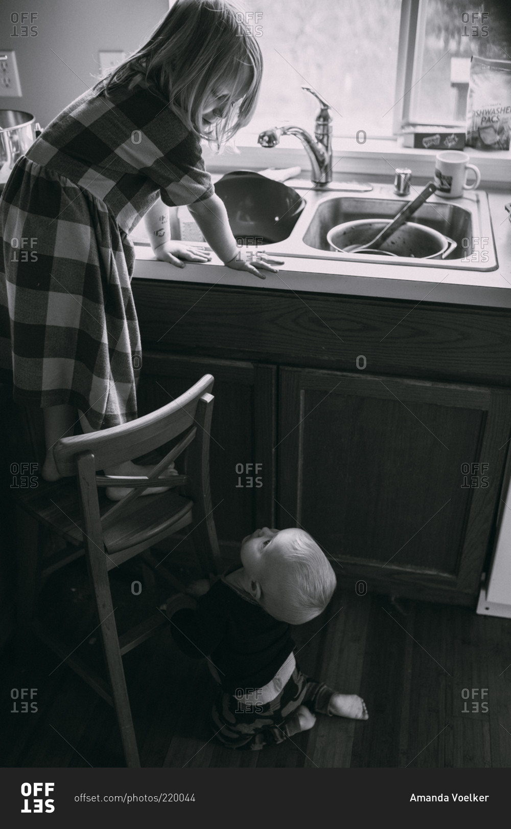 Boy watching sister wash the dishes