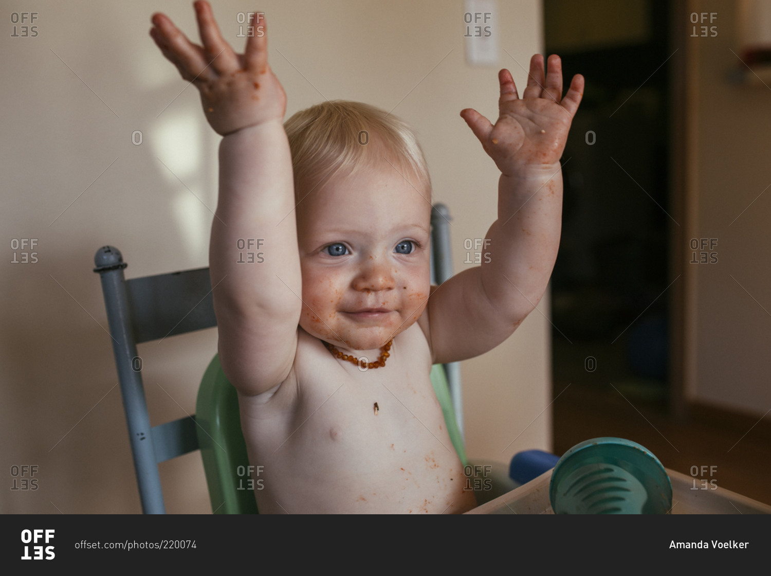 Portrait of toddler boy in high chair throwing hands up stock photo
