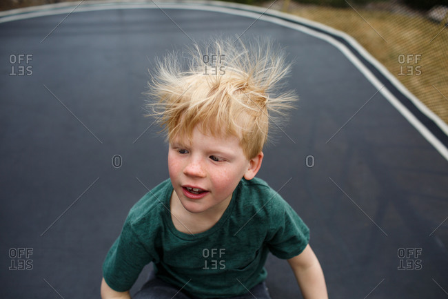Static electricity in boy's hair on trampoline stock photo - OFFSET