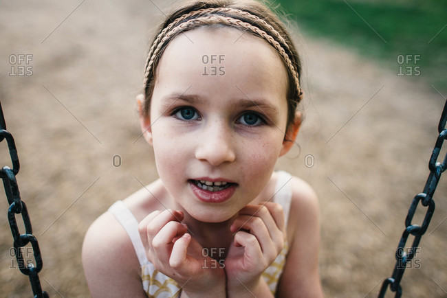 Portrait of a young girl with freckles sitting on a swing