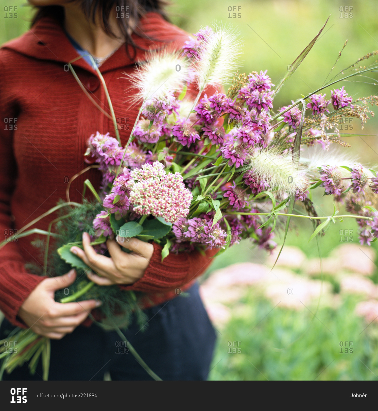 A woman holds a bouquet of purple flowers