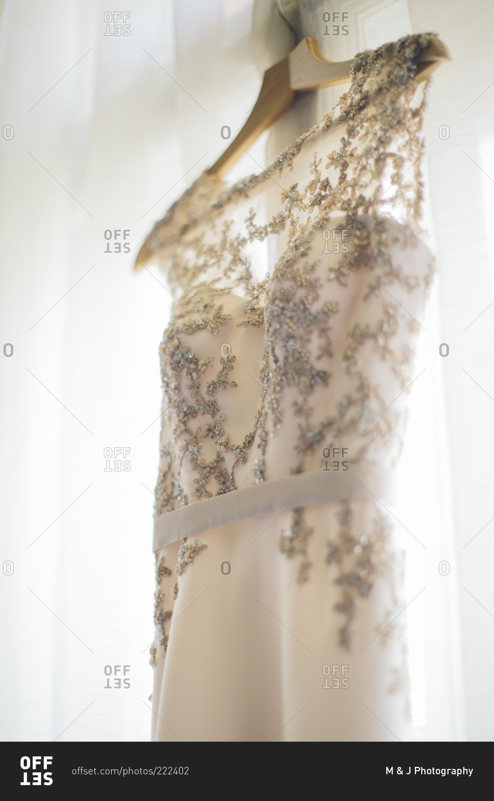 Elegant wedding dress hanging by the window