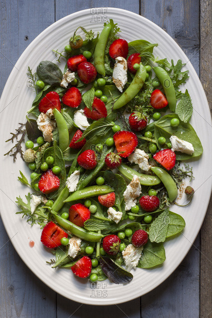 A salad of greens, sugar snap peas, strawberries, mint and goat cheese with a balsamic vinaigrette