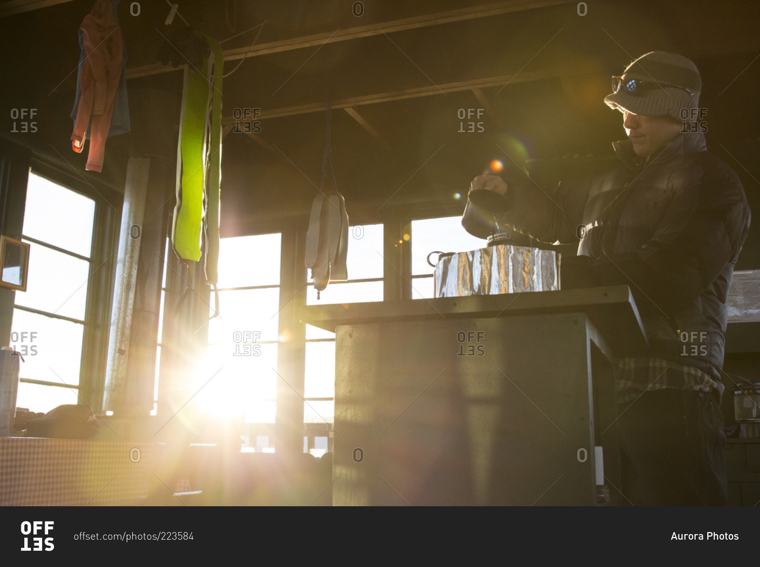 A man boils water on his camp stove in a fire lookout tower in Montana during winter