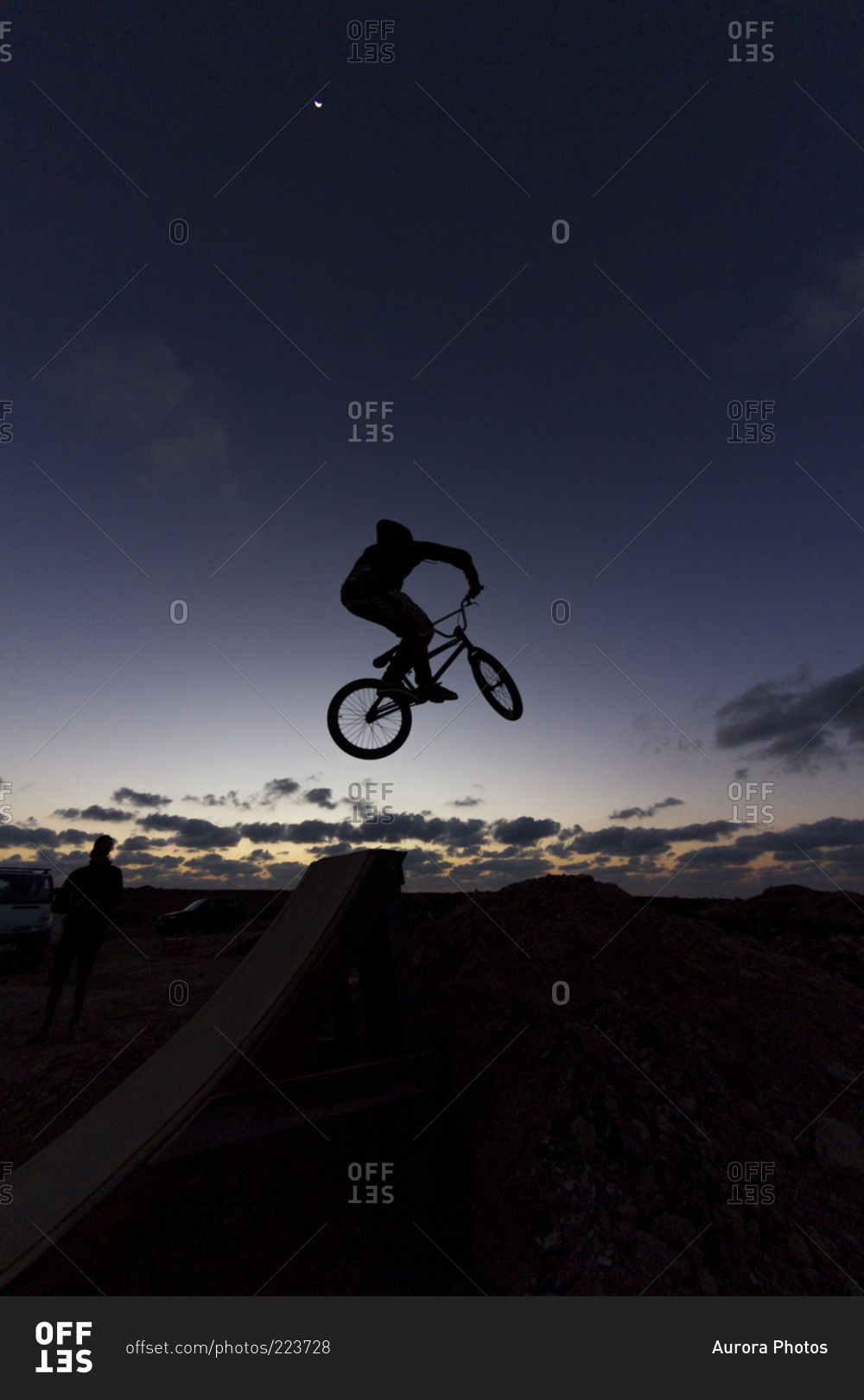 Silhouette of a person with bmx jumping at dusk
