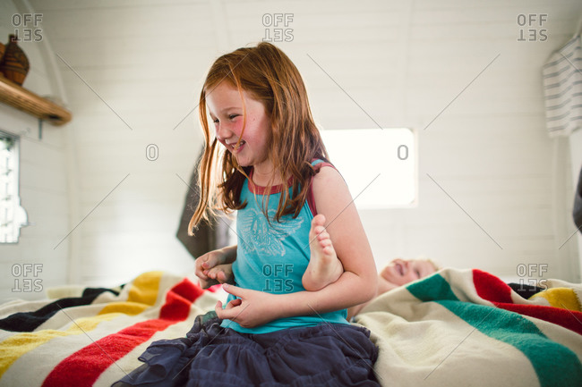 Girl Tickling Foot Of Boy On Bed Stock Photo OFFSET