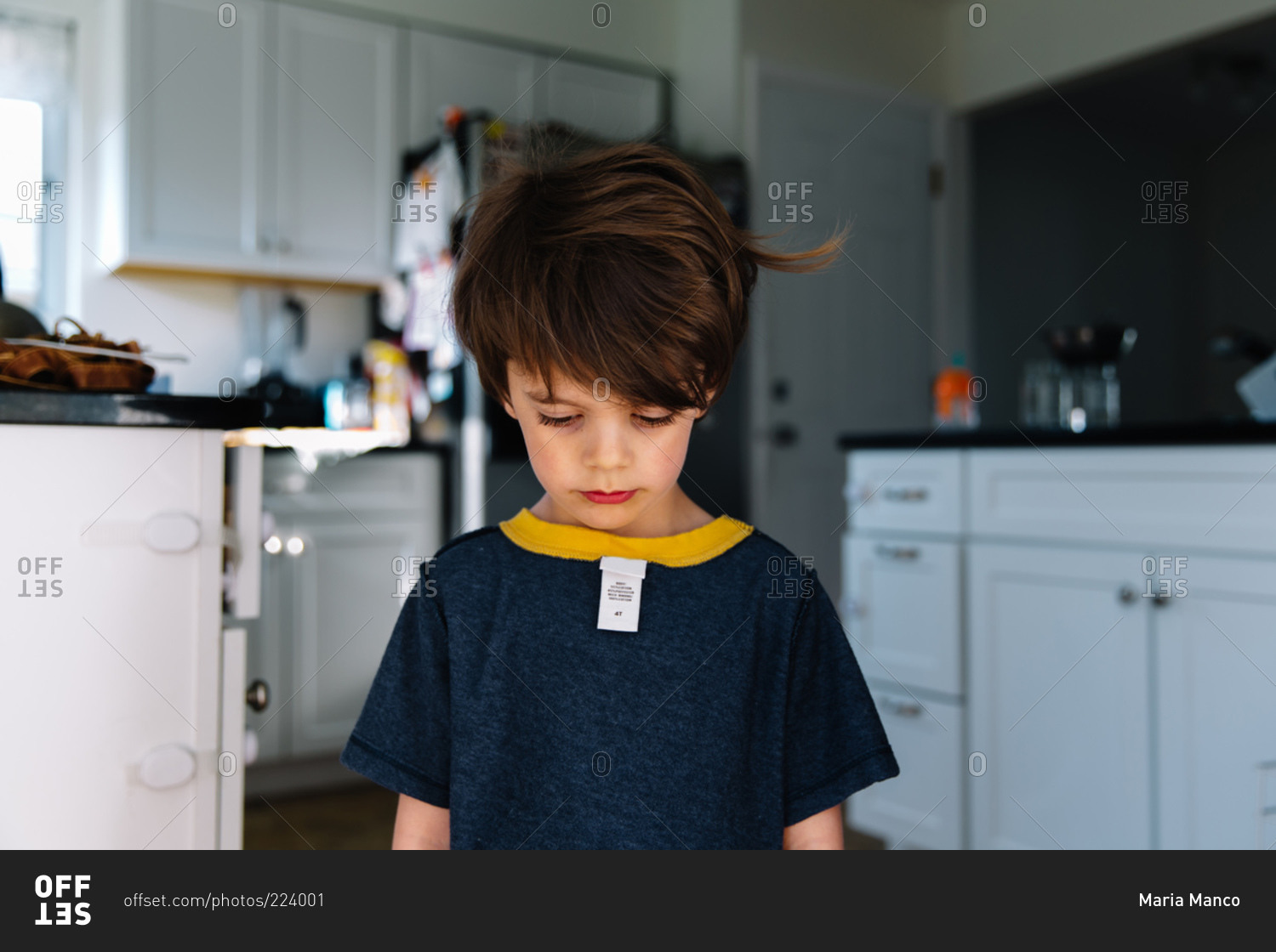 A boy stands in his kitchen with his shirt on backwards stock photo