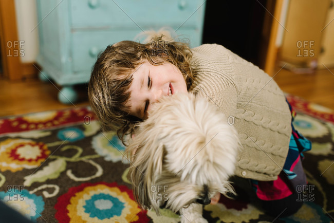 Girl giving dog a hug in home