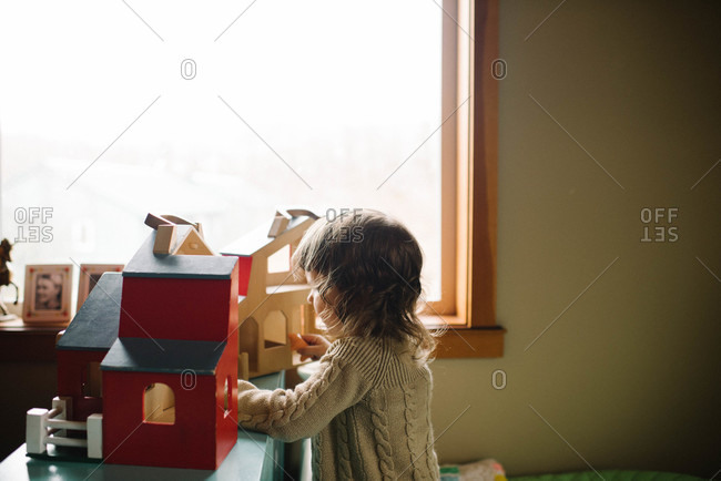 Girl playing with wooden house toy