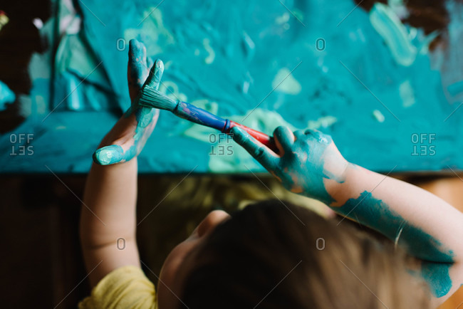 Girl painting her fingers and table