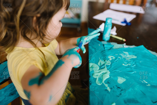 Young girl painting her hand and table