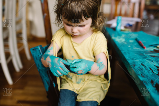 Girl with paint on hands and table