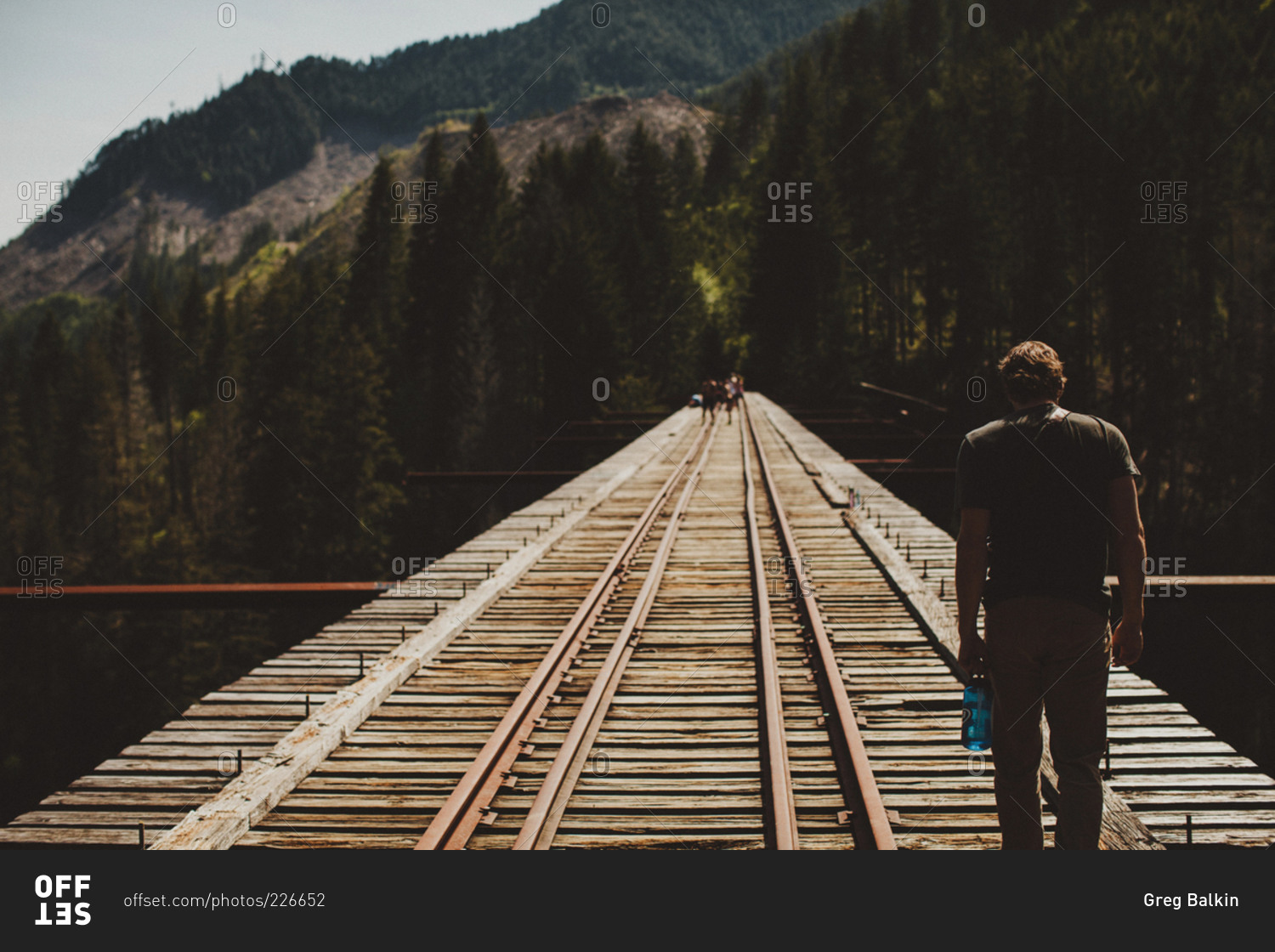 A young man walks down train tracks across a bridge in Mt. Baker