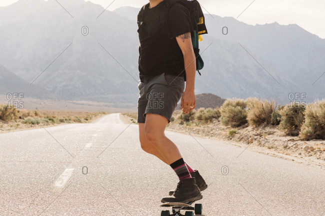 A man skateboards down a desert road