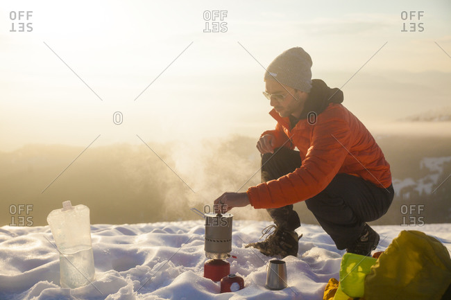 A climber attends to his boiling water on a camping stove while camping in the mountains of British Columbia, Canada