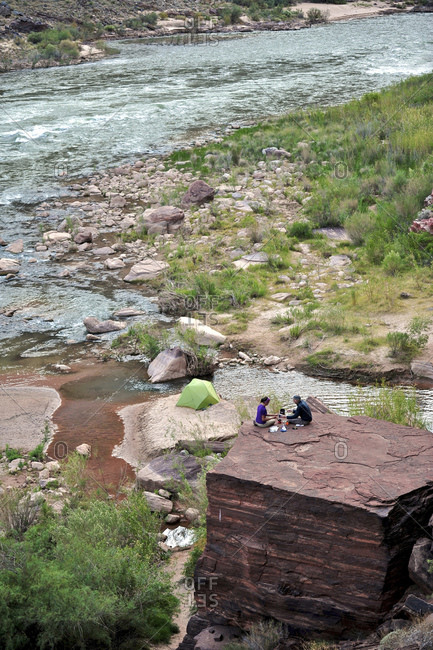 Hikers cook dinner on a cliff-pinched patio above the Colorado River near Deer Creek Falls in the Grand Canyon