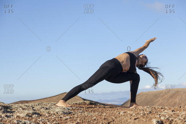 Girl practicing yoga on the top of a volcano in Fuerteventura, Canary Islands