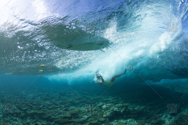 Surfers wiping out on the shallow reef in maldives