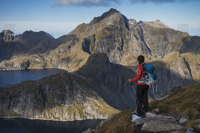 Female hiker takes in view of mountains from trail to Munken, Moskenesøy, Lofoten Islands, Norway
