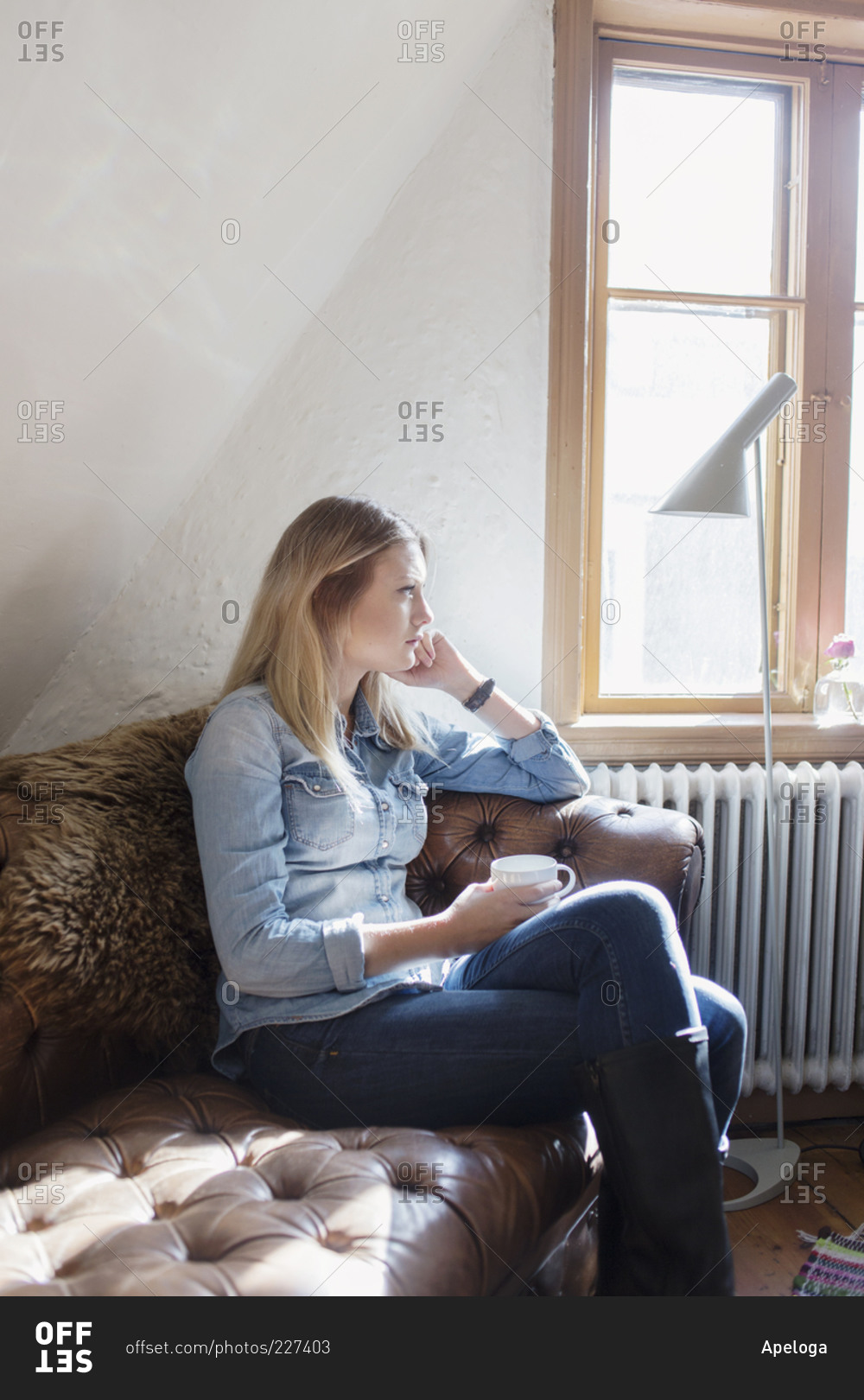 Young blonde woman sitting on a pillow stock photo - OFFSET