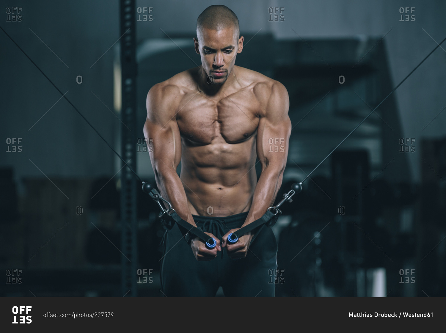 Young man training pectoral muscles at cable crossover in gym