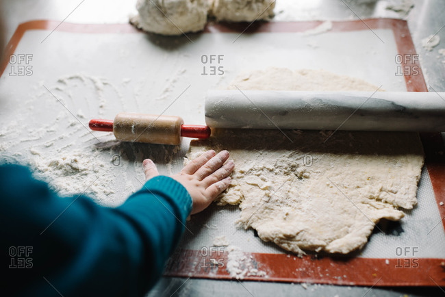 Child playing with dough and rolling pins