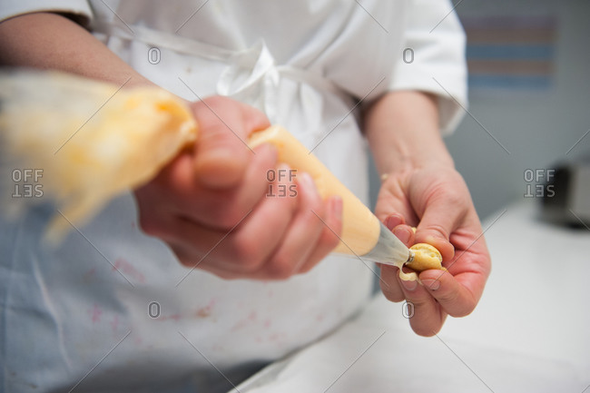A chef fills a pastry with creme filling