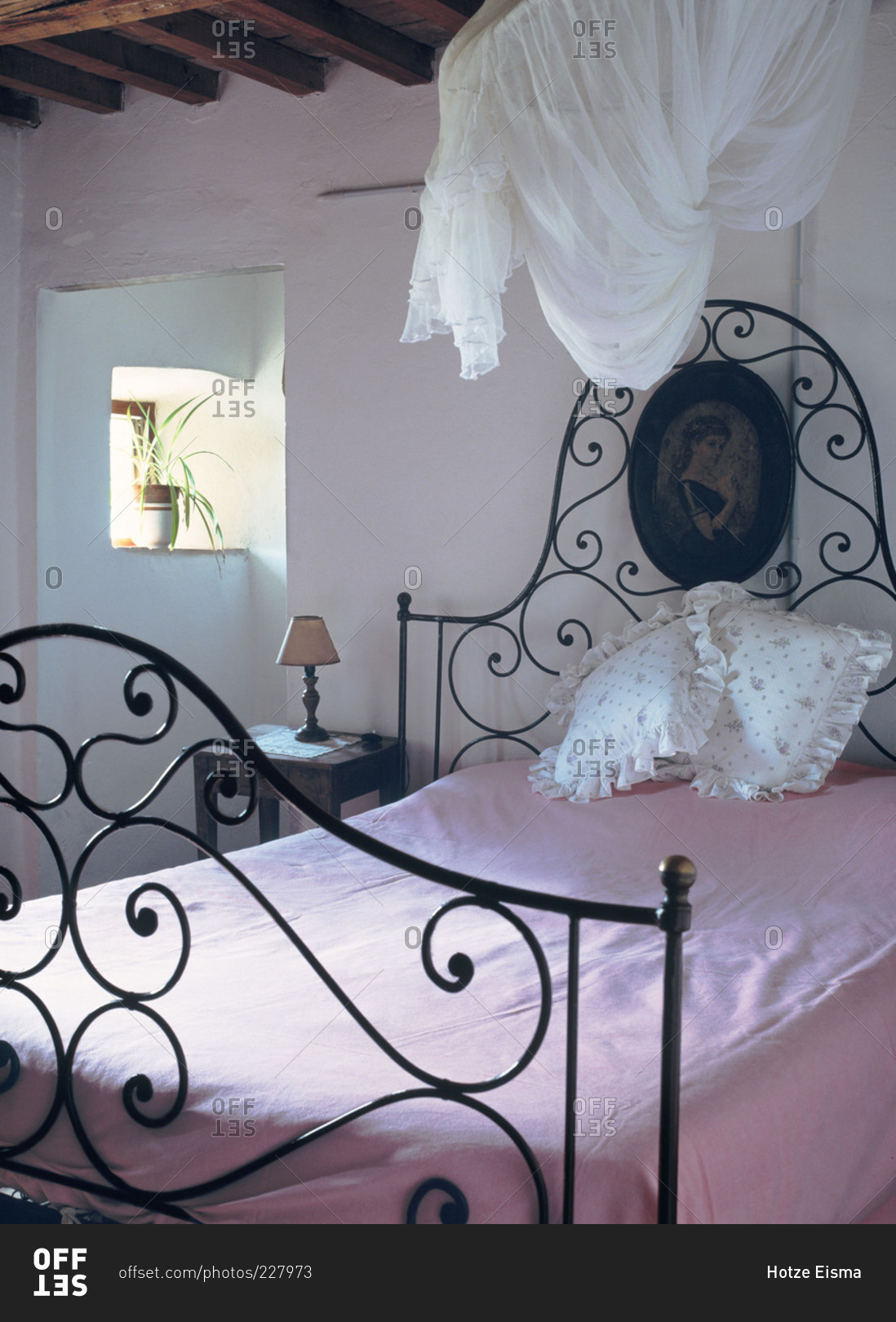 Room with an iron bed and pink blanket