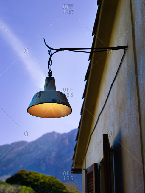 Old weathered lamp hanging off a stucco cottage