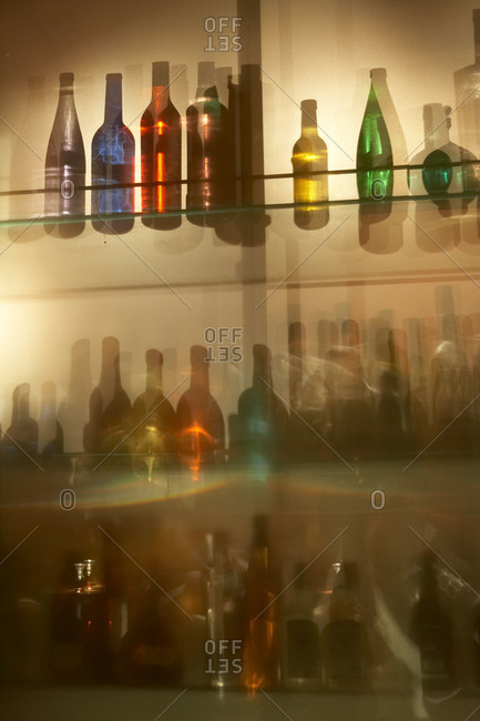 Different colored glass bottles seen through a translucent bar window