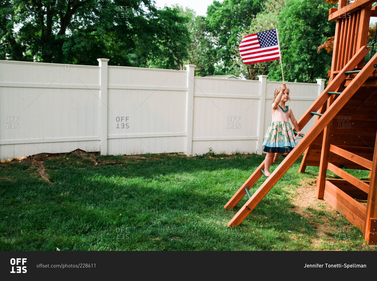 Child climbing up a wooden play structure with an American flag