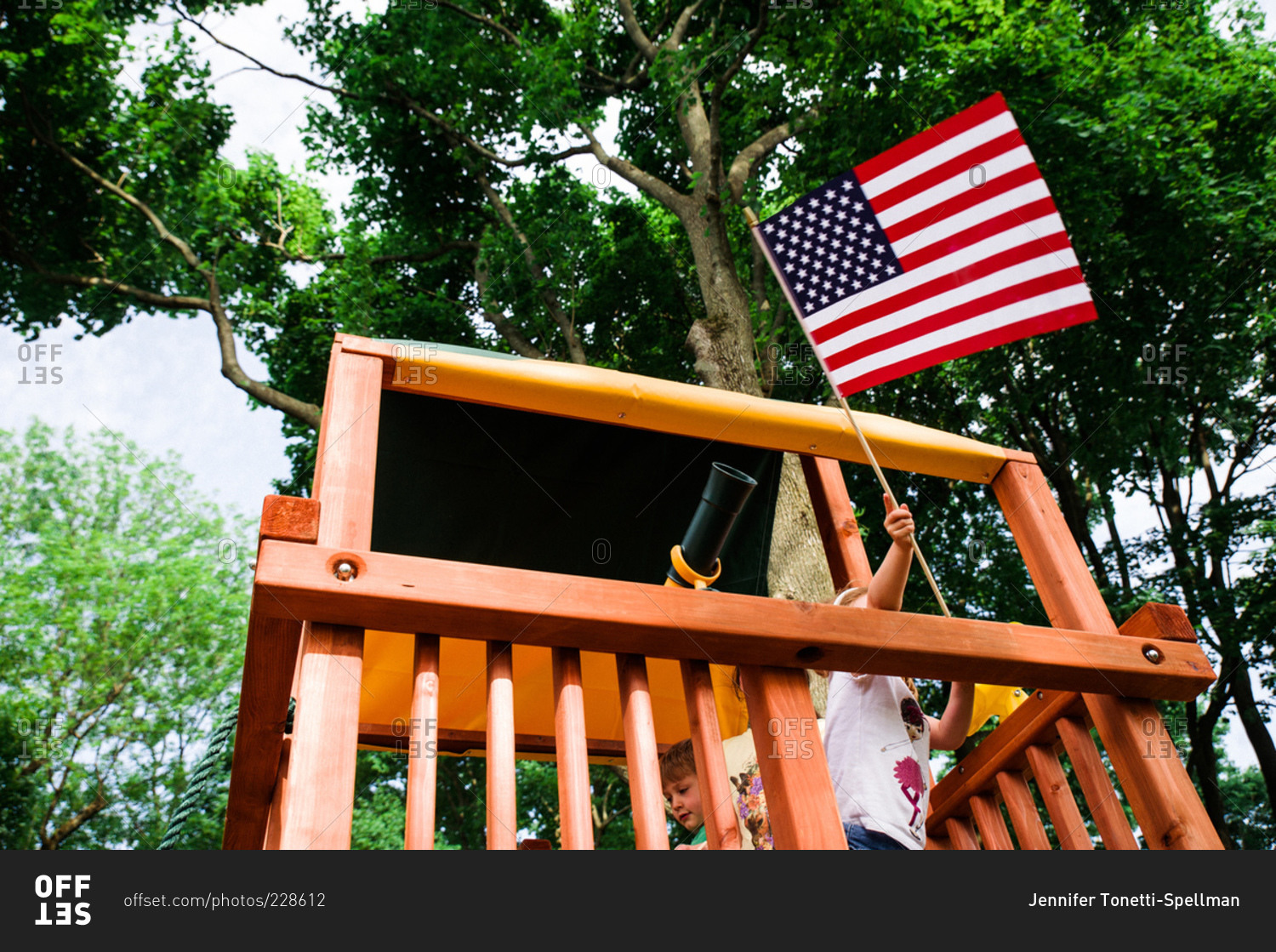 Child waving an American flag out of a play fort