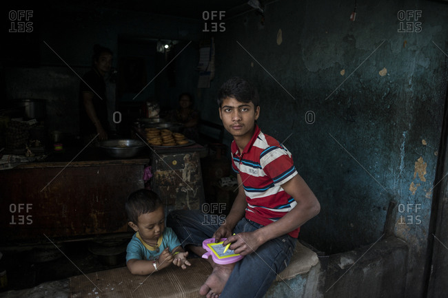 Kathmandu, Nepal - June 2, 2014: A young man takes care of his little brother