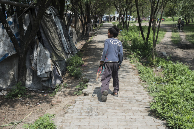 Kathmandu, Nepal - May 29, 2014: A little boy walks down a path next to shacks in the slums of Thapathali, Kathmandu, Nepal