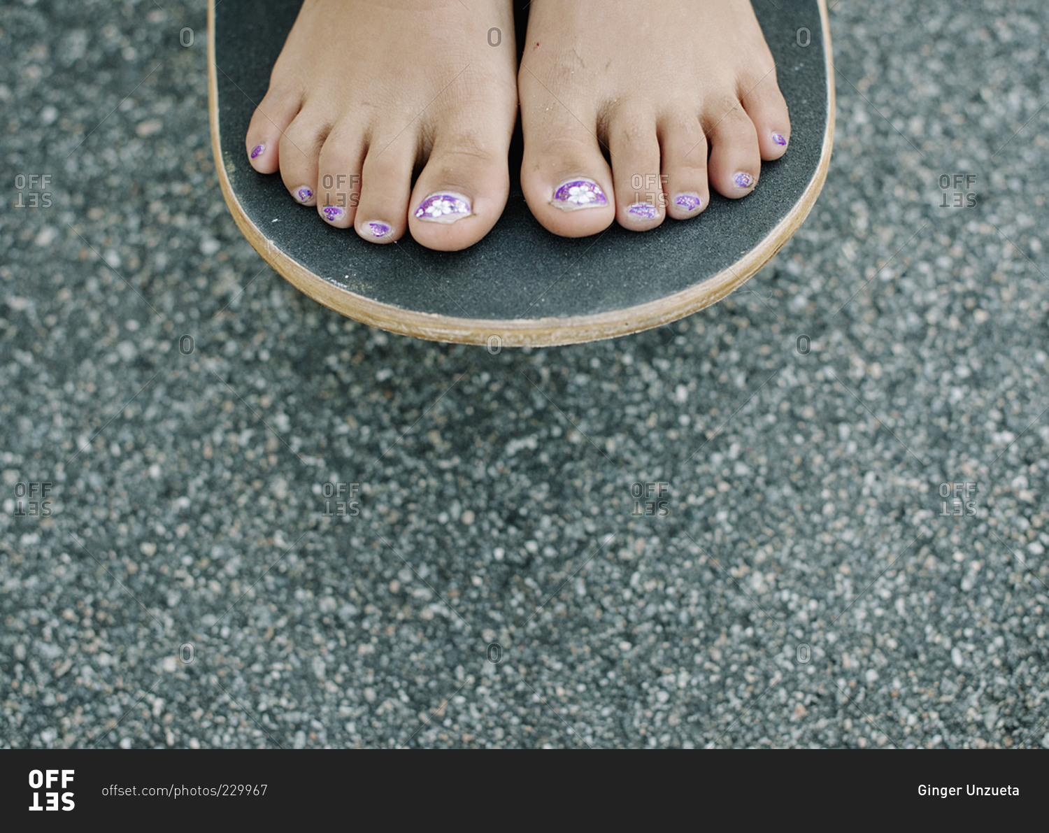 Close-up of young girl's painted toenails on a skateboard