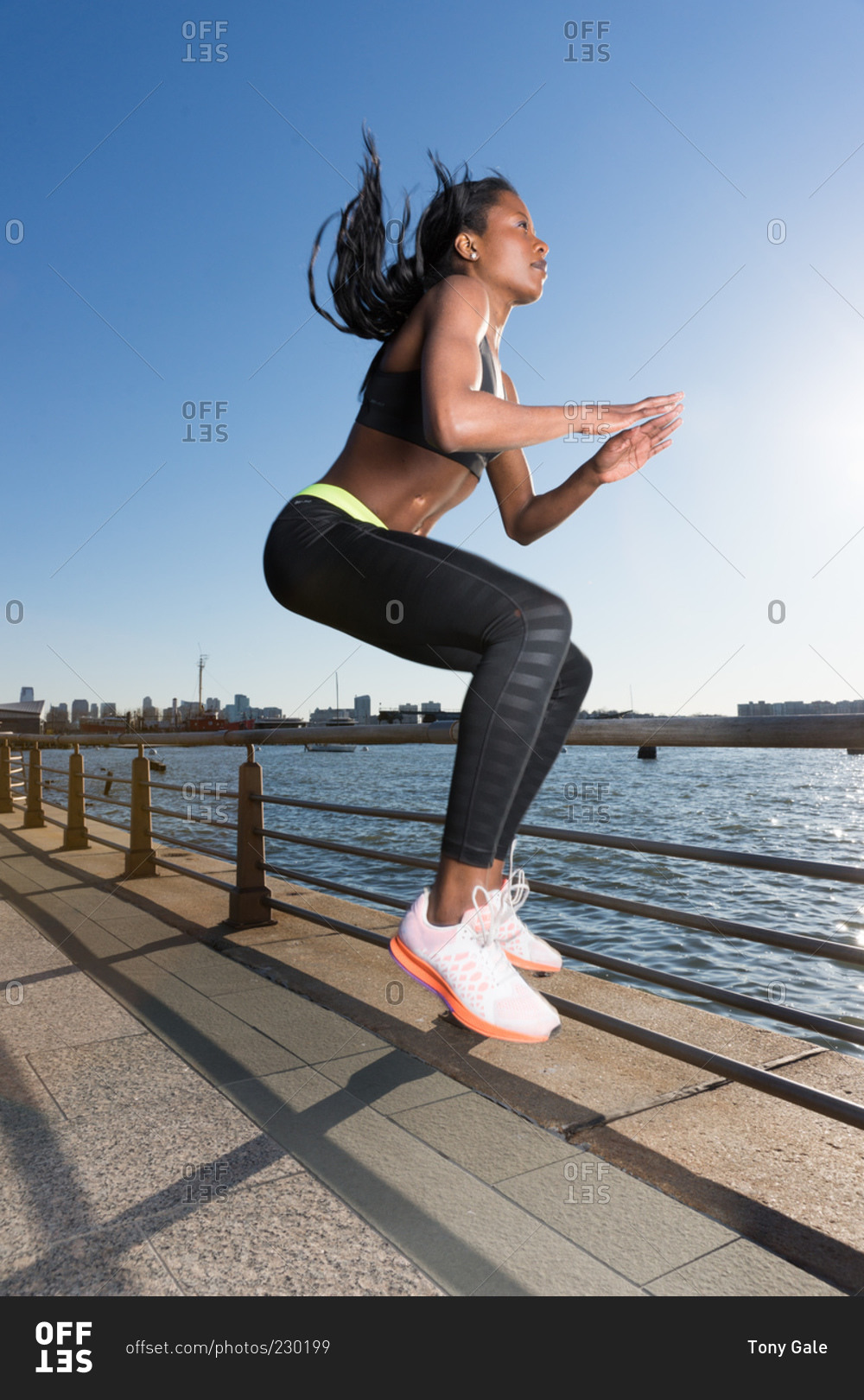 Athletic woman doing jump tucks at oceanside park