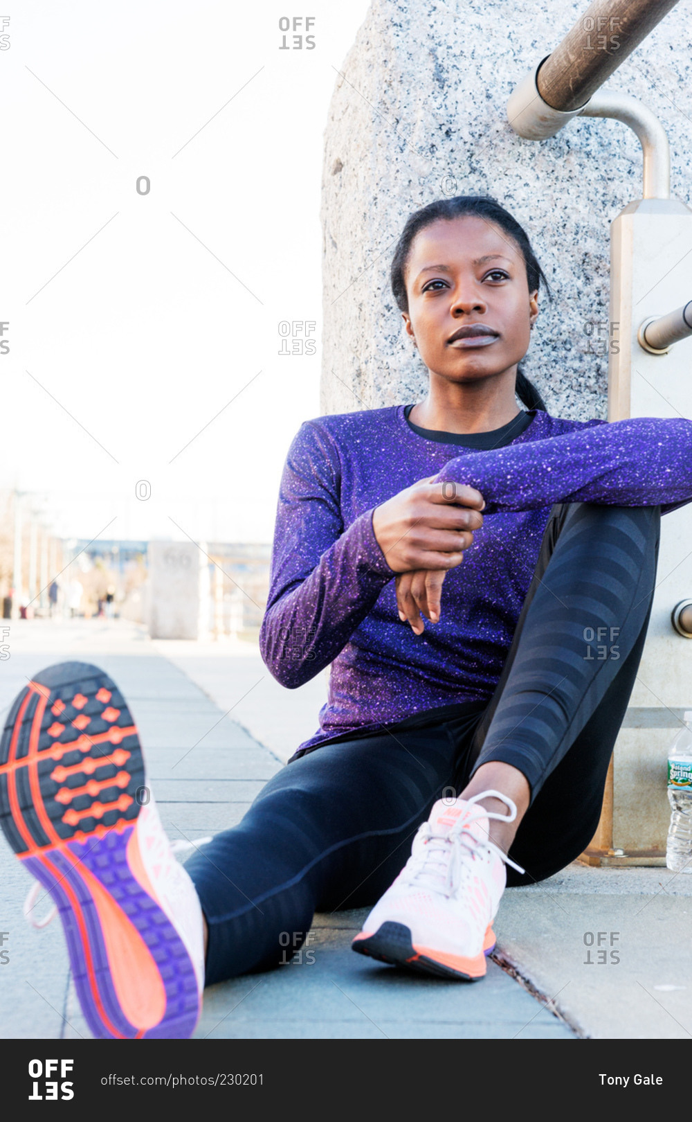 Athletic woman sitting against railing resting
