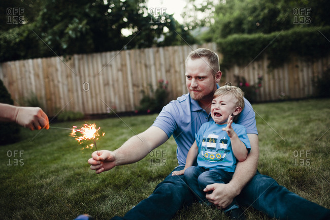 Man holding sparkler with frightened boy