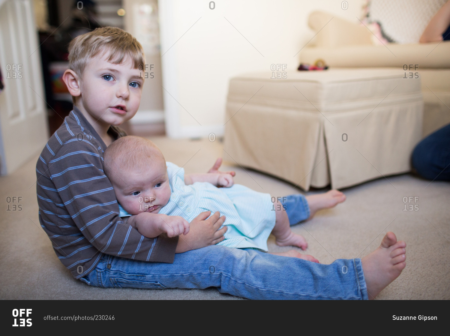 Boy with baby in lap on floor stock photo OFFSET