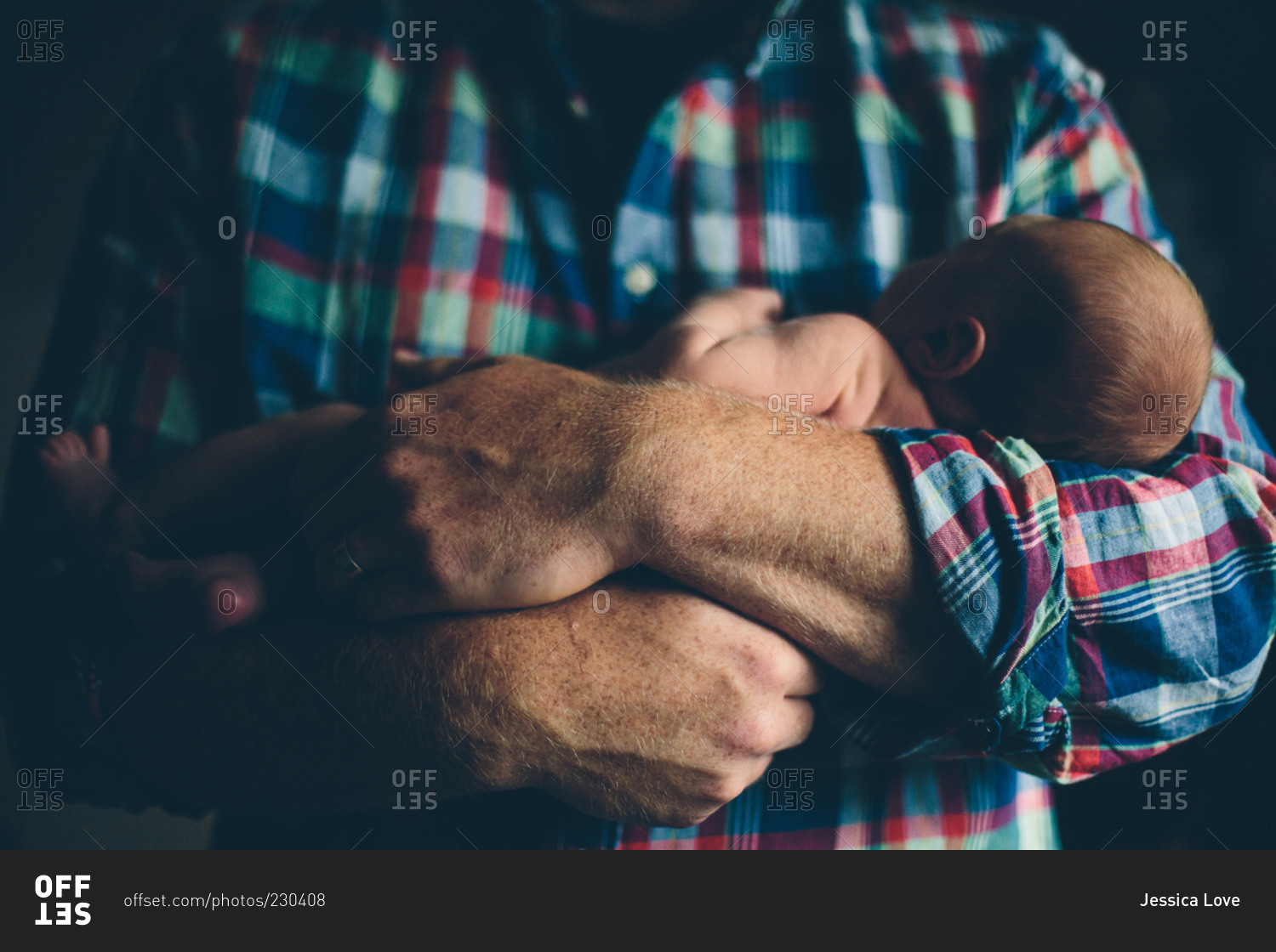 Newborn cradled in man's arms stock photo OFFSET