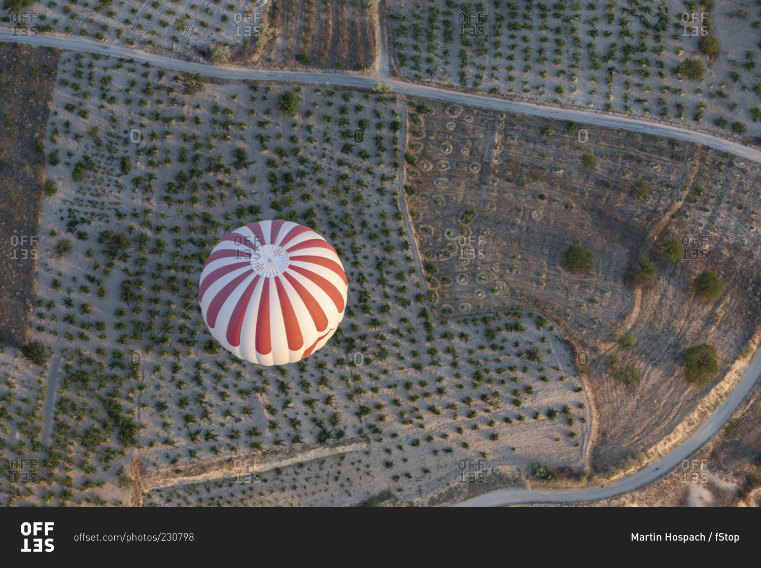 High angle view of striped hot air balloon flying over agricultural landscape