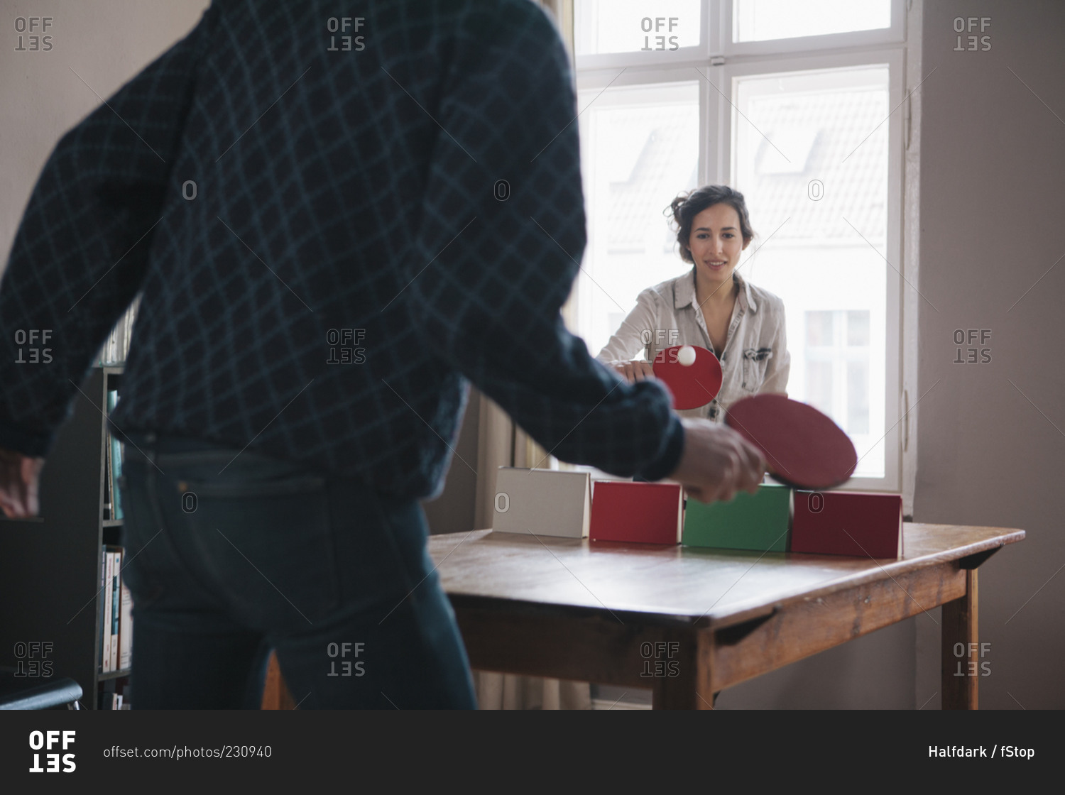 Young woman playing ping pong with man at home