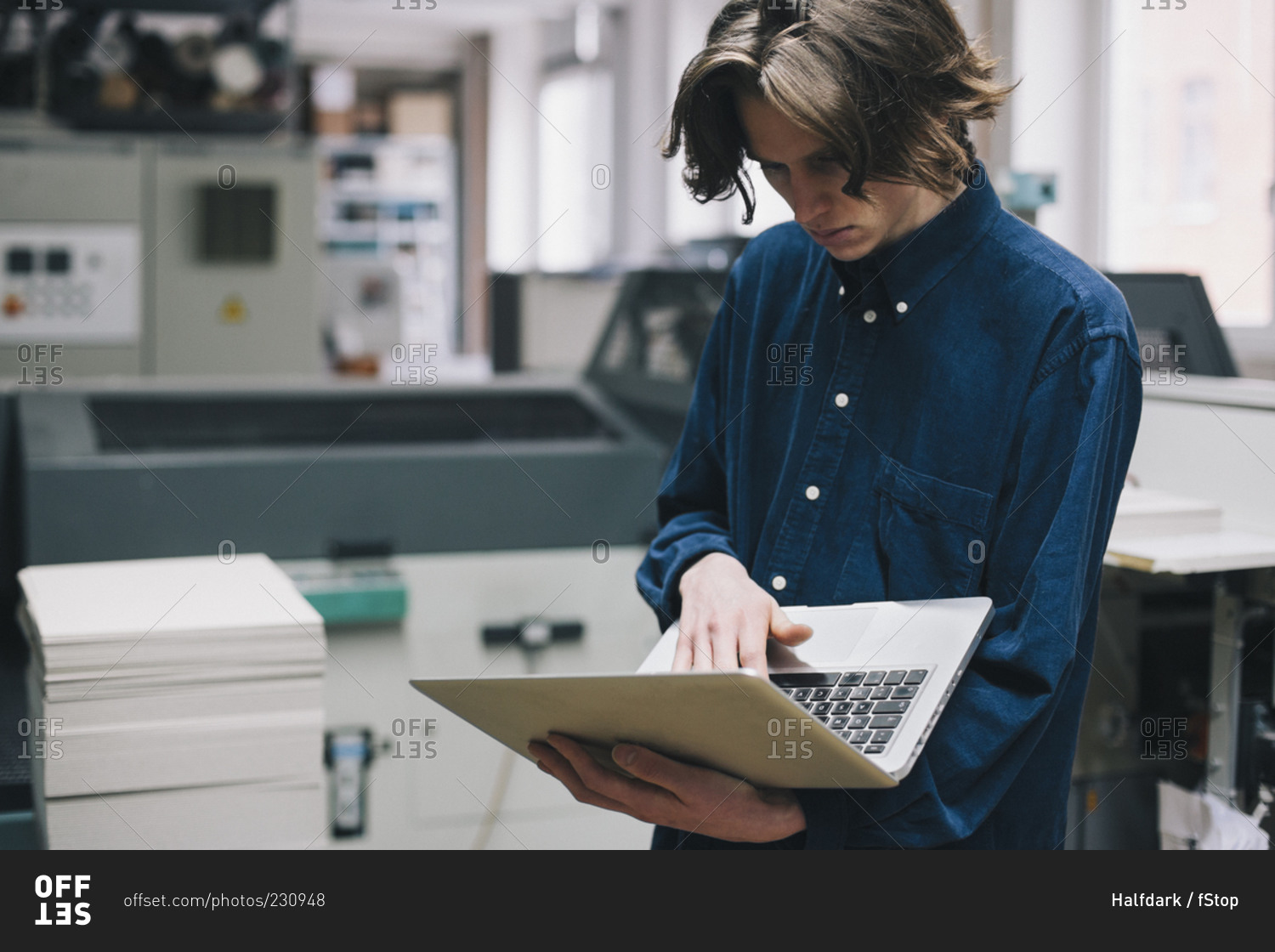 Young male technician using laptop in factory