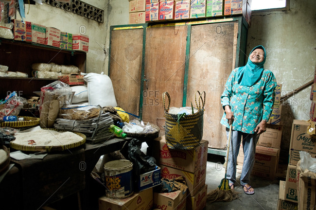 Yogyakarta, Indonesia - May 29, 2015: An Indonesian woman laughs while sweeping the floor of her shop
