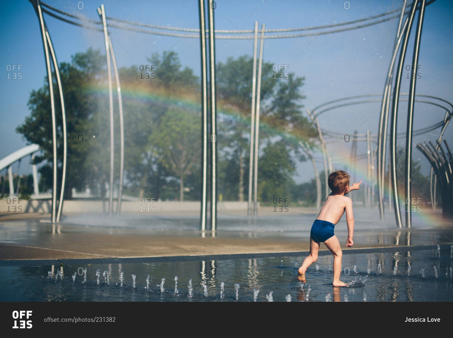 Little boy running through city fountain