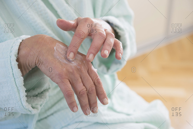 Senior woman applying moisturizer on her hand