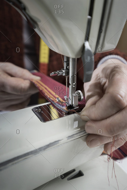 Senior female fashion designer stitching in workshop